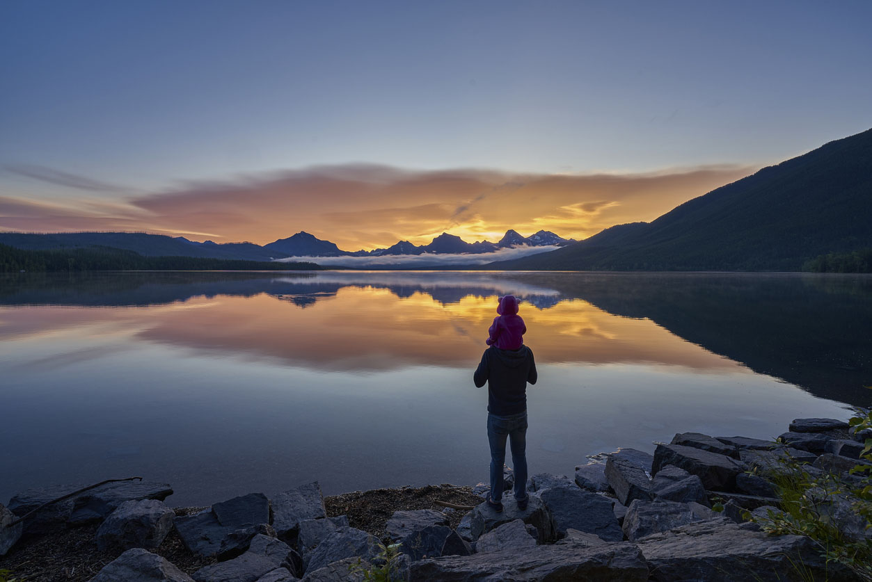 Father and Daughter Looking at a Vibrant Sunrise in the Beautiful Natural Scenery of Glacier National Park's Lake McDonald Area During the Summer in Montana, USA.